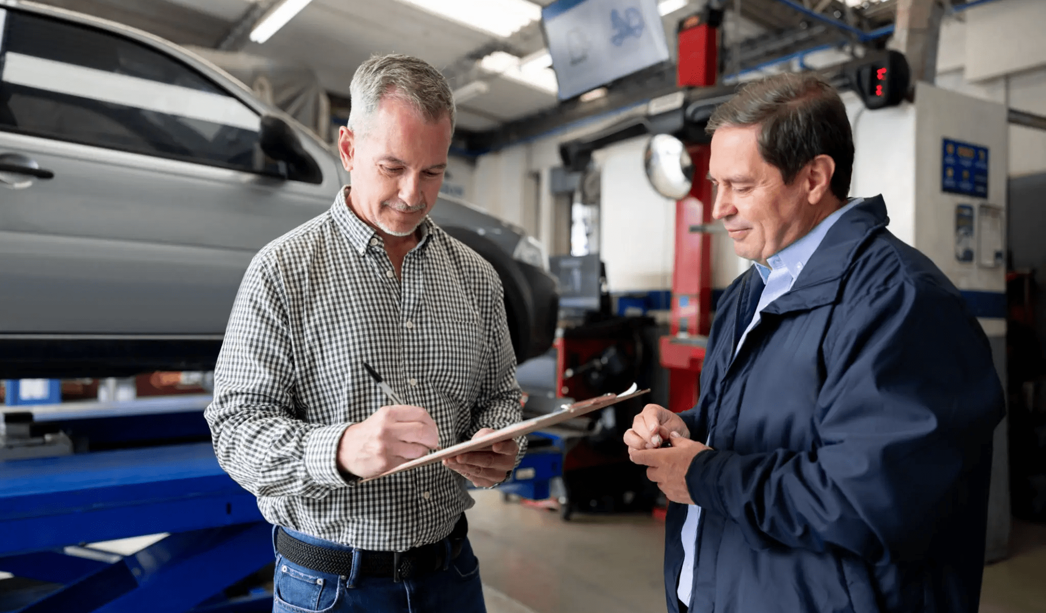 Two men discussing in an auto repair shop.