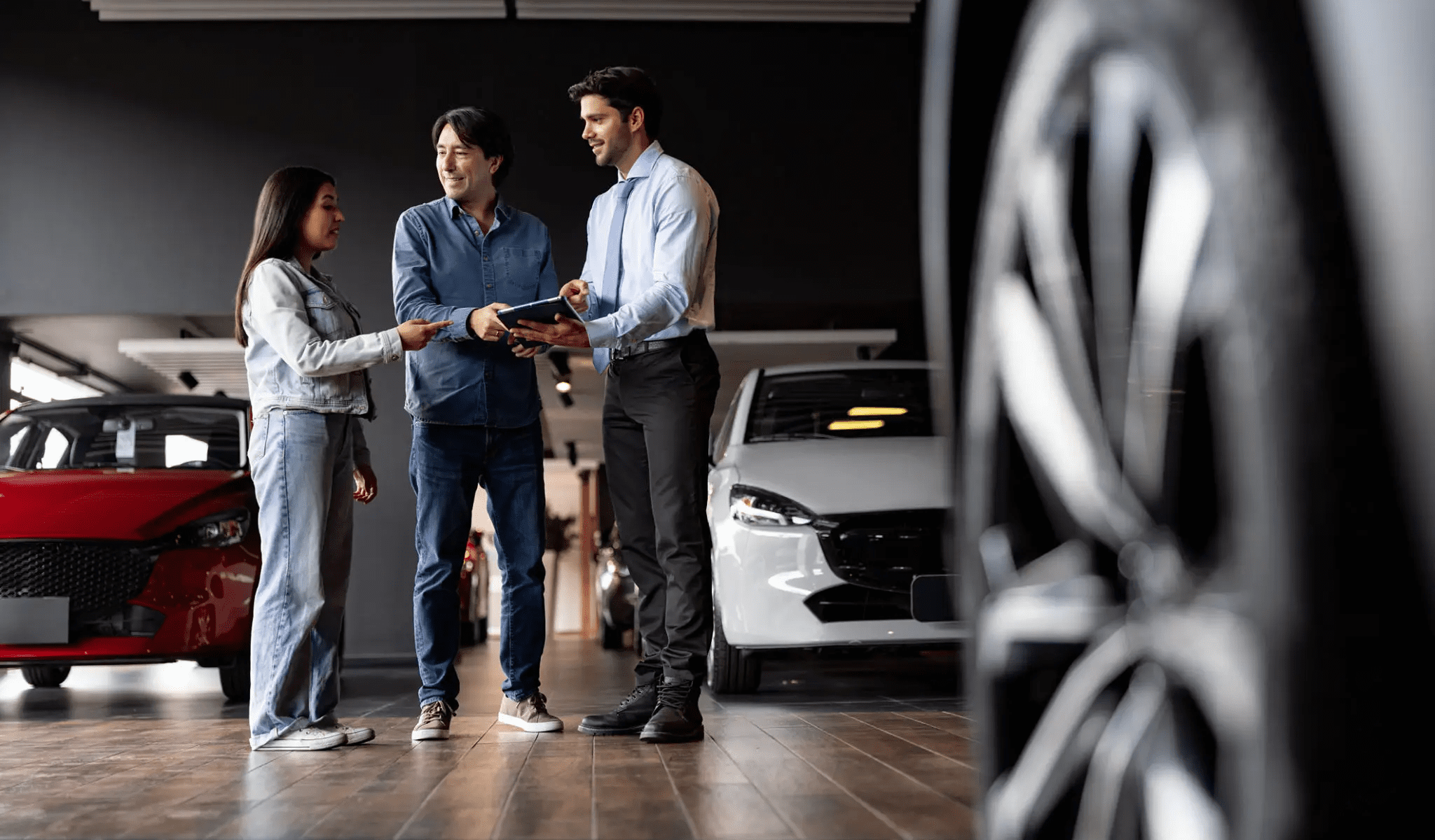 Car dealership customers discussing with salesman.