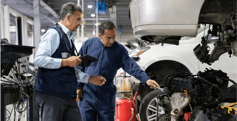 Mechanics inspecting car engine in repair shop.