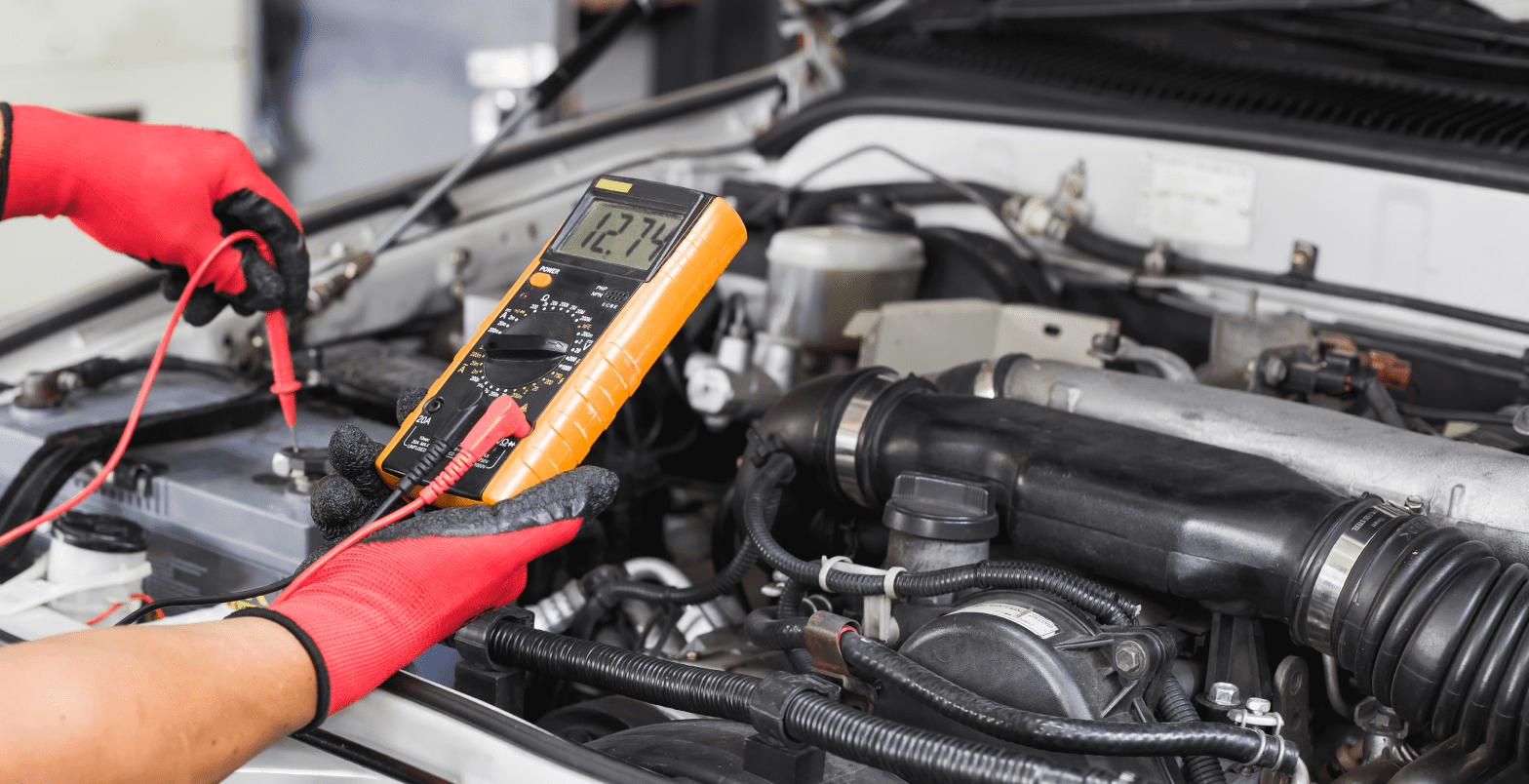 Mechanic using multimeter on car engine